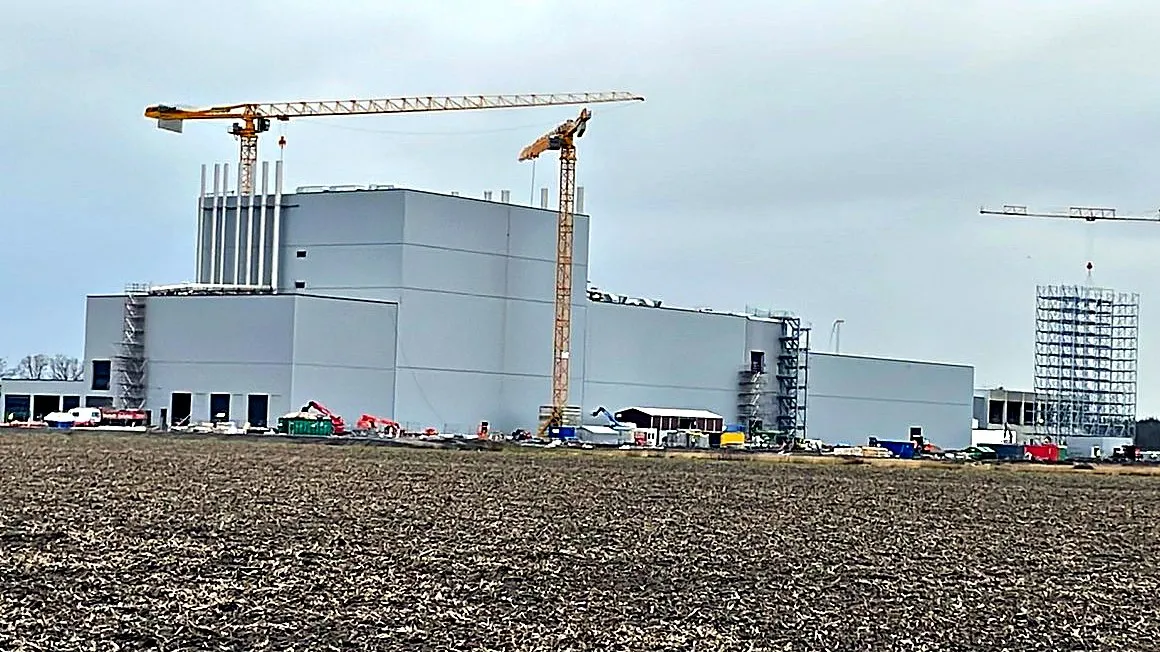 Großbaustelle der Kaffeerösterei in Rheine mit Kränen, gesehen über ein Feld
