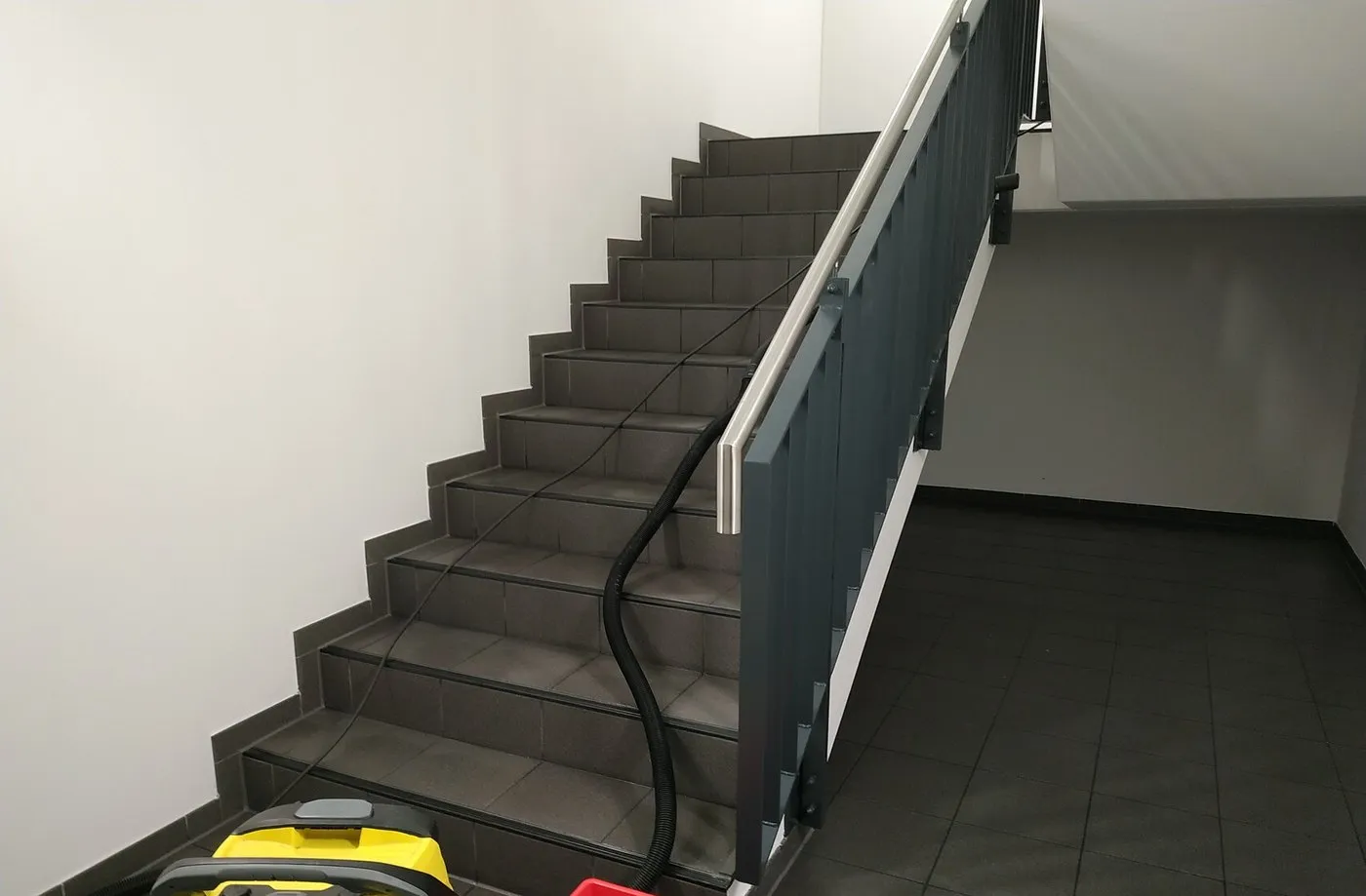 Treppenhaus während der Reinigung mit Sauger und Eimer